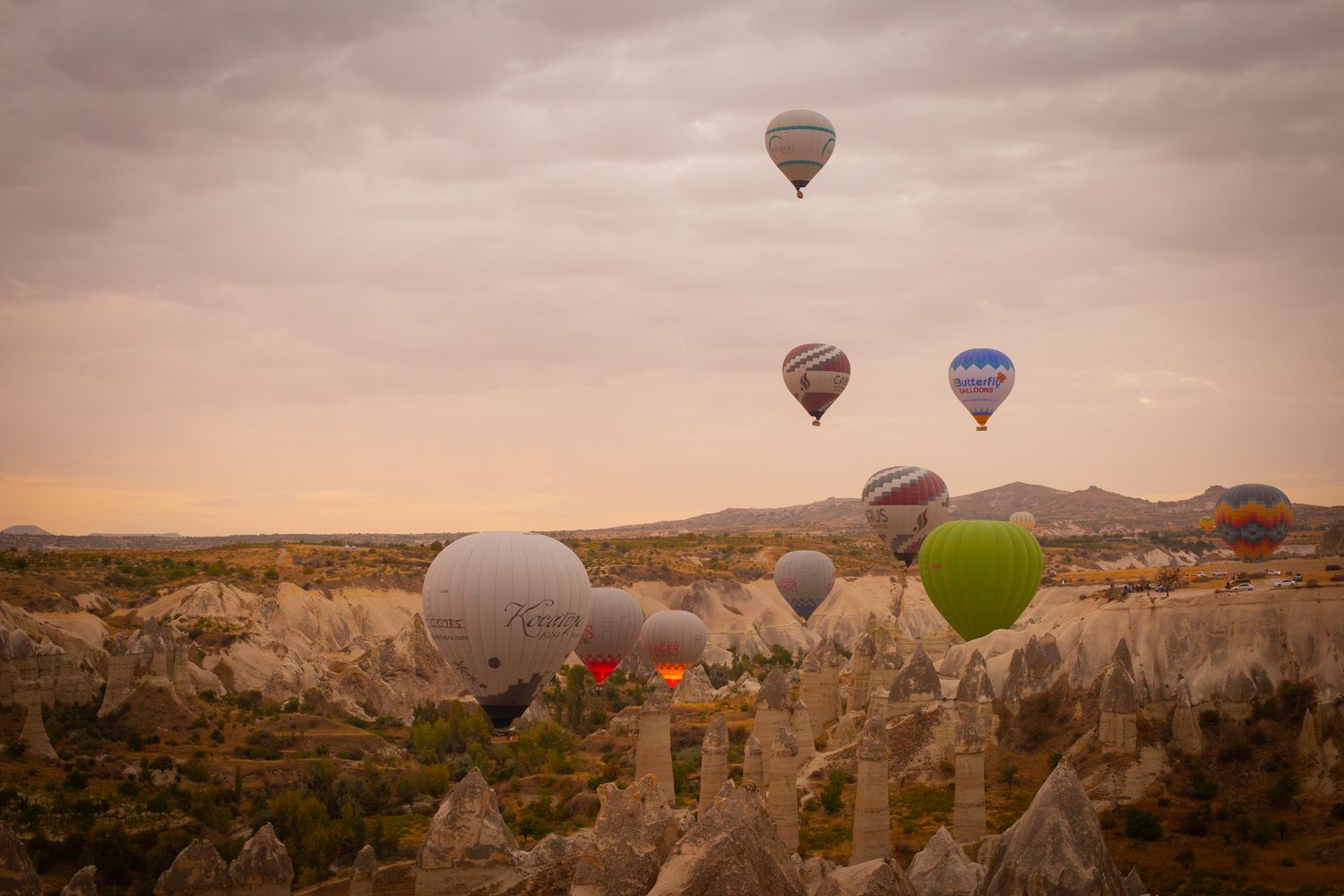 Dozens of hot-air balloons rising over the rock valleys of Cappadocia at sunrise