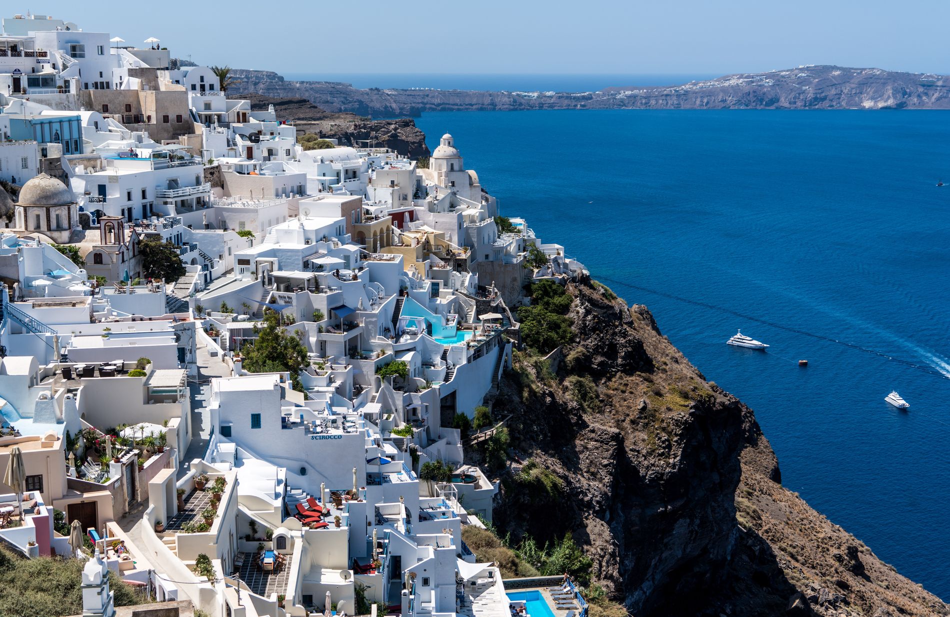 Whitewashed village above the deep-blue Aegean Sea in Santorini, Greece at golden hour